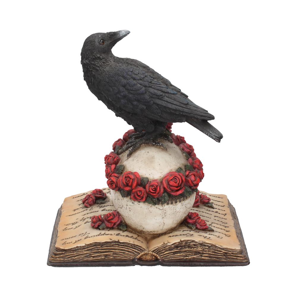A black raven statue perches atop a rose-adorned skull, which rests on an open book with illegible text, set against a plain background.