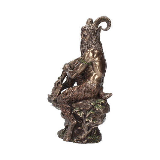 A bronze-colored statue of a satyr plays a pan flute while seated on a rocky outcrop with leafy vines, showcasing a blend of animal and human features.
