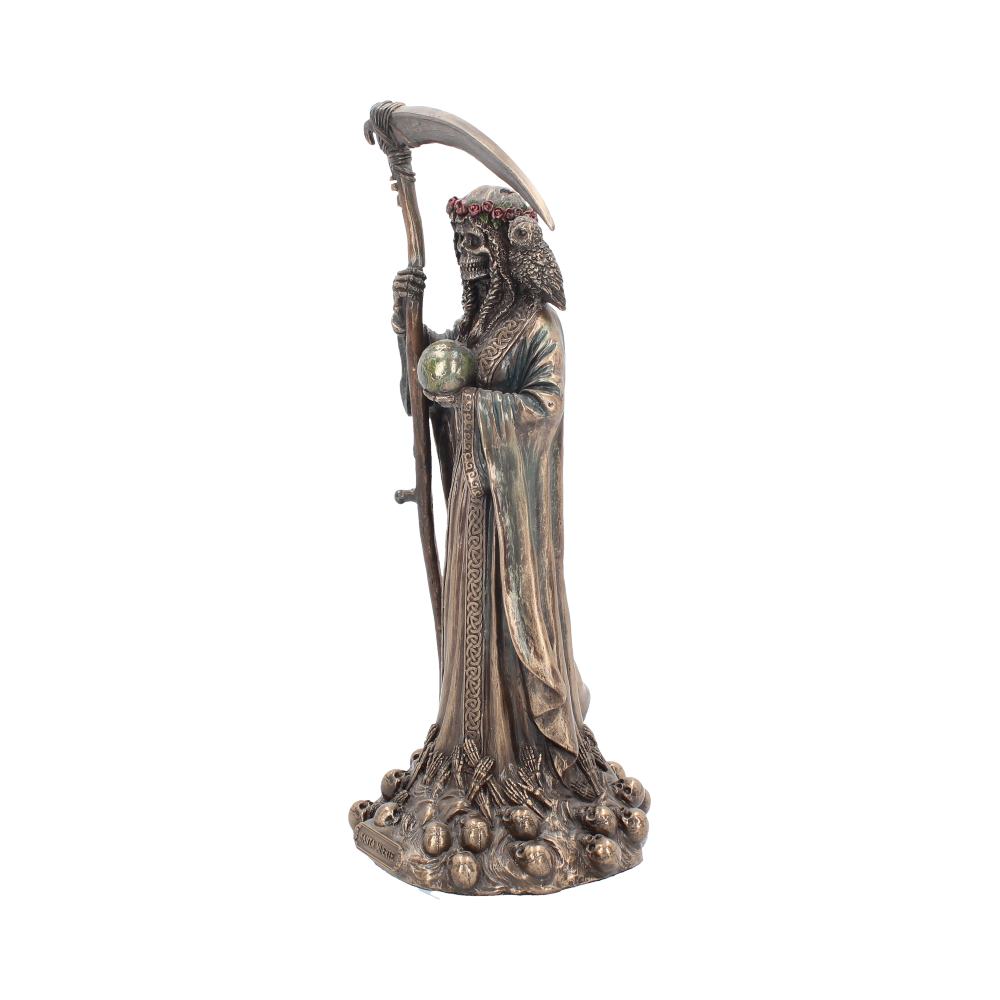 A bronze-colored reaper statue stands on a pile of skulls, holding a small green sphere and a scythe. The figure has a crown of red flowers and is draped in a robe.