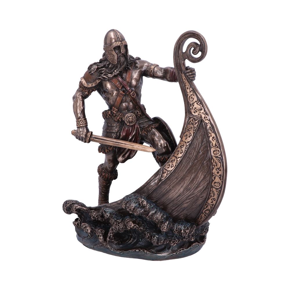 A detailed bronze sculpture depicts a Viking warrior grasping a ship's ornate prow with one hand while brandishing a sword, surrounded by stylized waves, suggesting motion and battle.