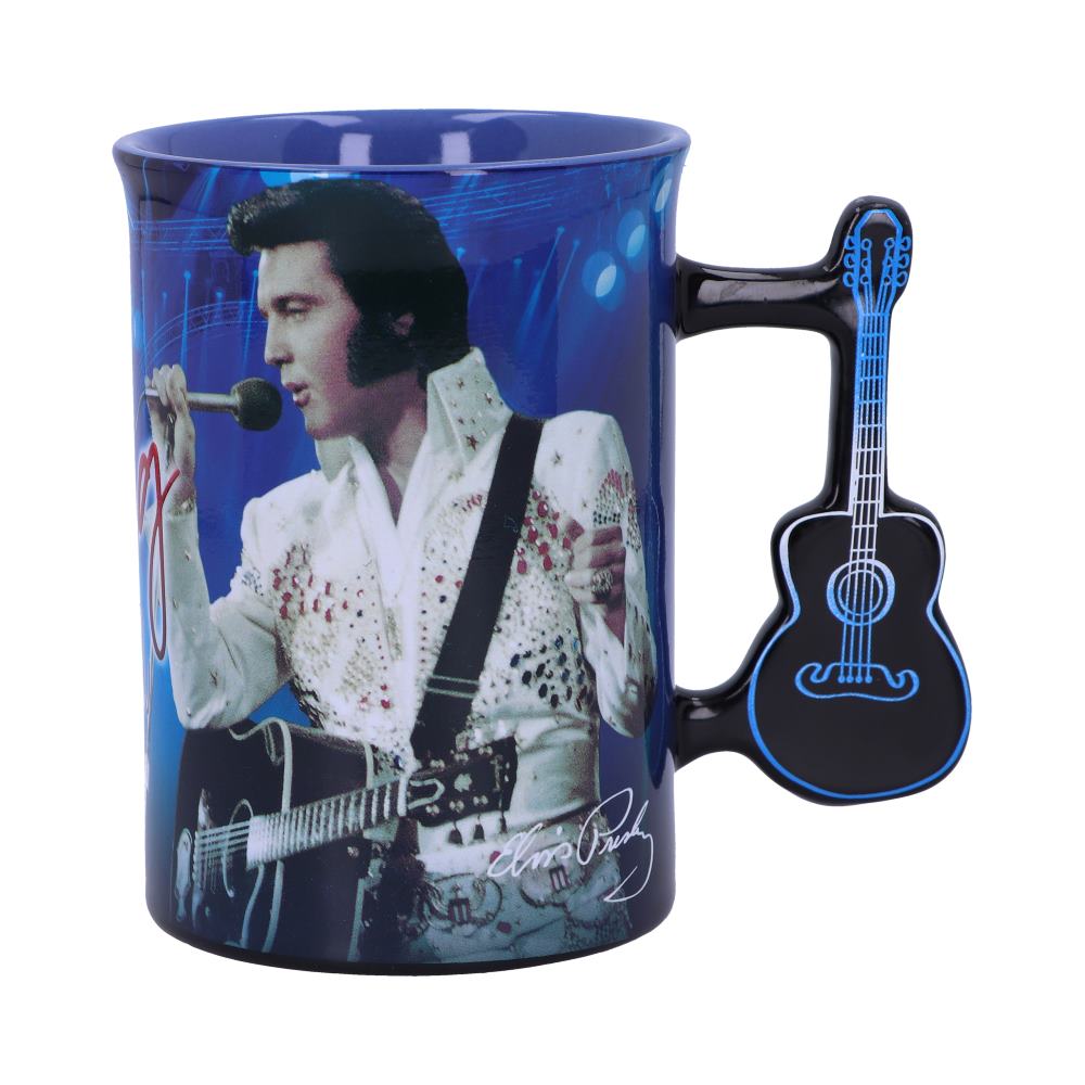 Mug features a performer in a white embellished jumpsuit singing into a microphone, holding a guitar against a blue-lit stage. The handle is shaped like a black guitar. Signature reads "Elvis Presley."