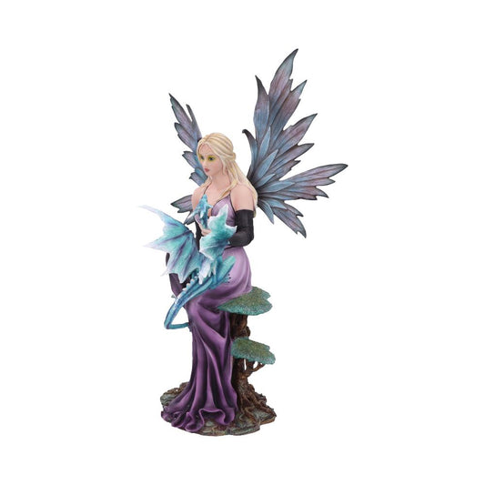 A fairy figurine with large wings sits, cradling a small, blue dragon in her arms. She is seated on a mossy tree trunk, set against a plain white background.
