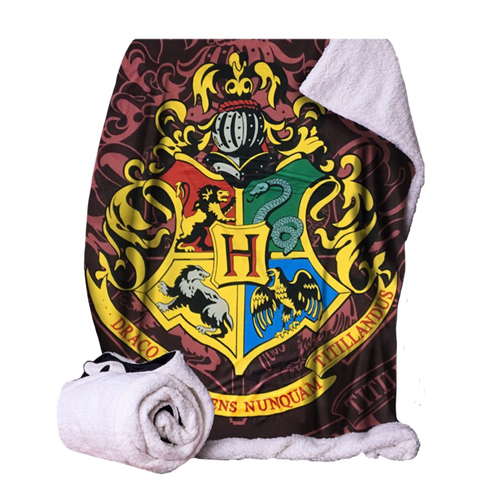 A blanket featuring a detailed colorful crest with animals and the letter "H," partially folded, against a patterned background. Text reads "Draco Dormiens Nunquam Titillandus".