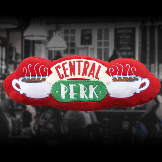 A red plush pillow, shaped like the Central Perk logo, displays the words "CENTRAL PERK" and two coffee cups; it rests against a blurred street background.