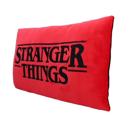 A rectangular red pillow displays the embroidered text "STRANGER THINGS" in black. It sits against a plain white background.
