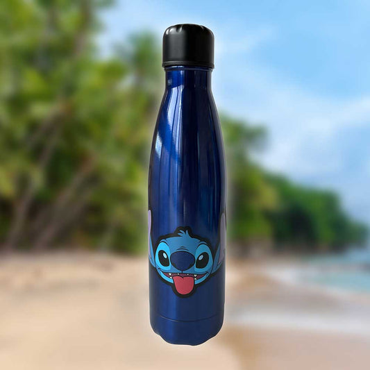 A blue water bottle with a black cap has an image of Stitch's face on it and is standing on a beach.