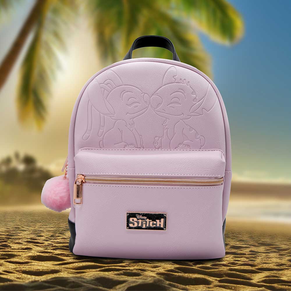 A lavender Stitch backpack rests on a sandy beach. Embossed Stitch characters adorn the front. A pink pom-pom zipper pull is visible. A rose gold "Disney Stitch" label is displayed.
