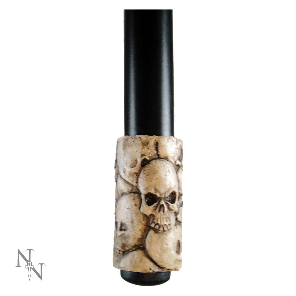 A walking stick handle, adorned with a skull motif, stands against a white background.