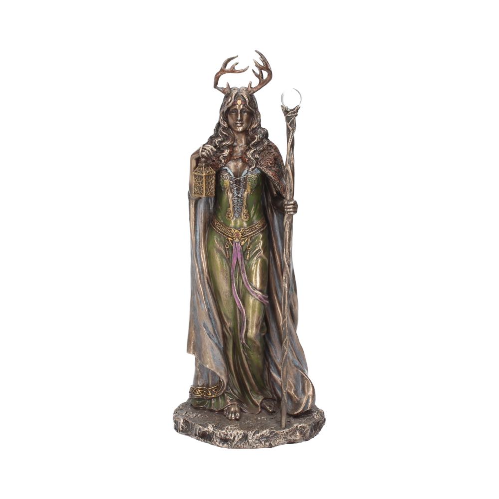 A bronze-colored statue depicts a woman with antlers wearing a green dress, holding a lantern and staff, draped in a cloak, standing on a textured base against a plain background.
