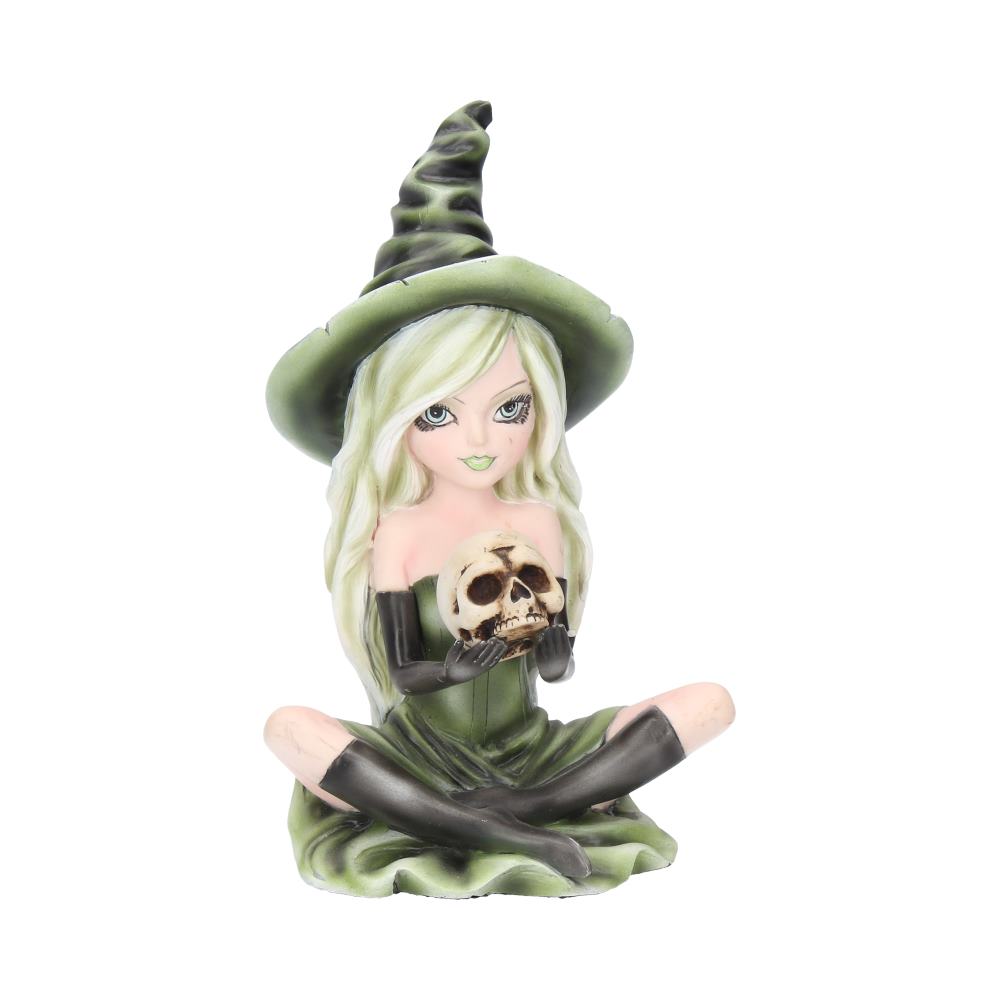 A figurine of a witch with long green hair and a pointy hat sits cross-legged, holding a skull. She wears a green dress and black gloves, set against a plain white background.