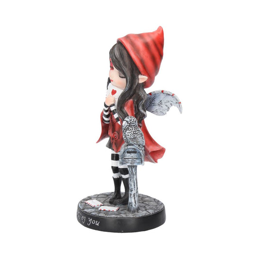 Fairy figurine in red hood kisses a heart-shaped card, standing beside a gray owl on a mailbox. Wings and striped stockings complete the whimsical scene. Base reads "Missing you."