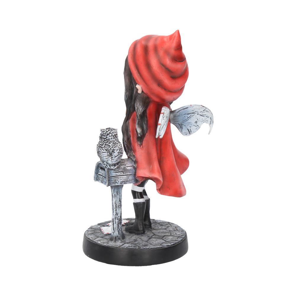 A figurine of a girl with wings wearing a red hood and cape stands on a circular base, facing an owl perched on a mailbox. The ground is stone-patterned.