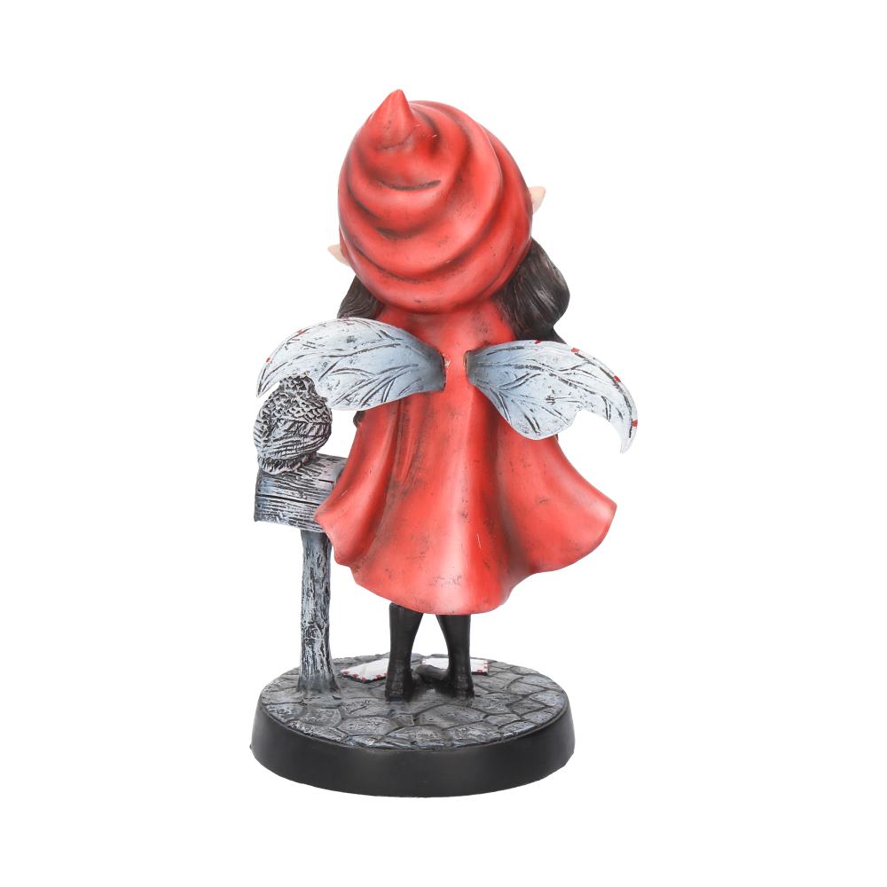 A figurine with butterfly wings and a red hood stands on a cobblestone base. Its back faces the viewer, and it leans against a textured post.