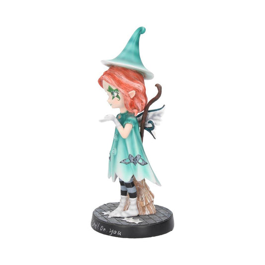 A small figurine of a whimsical fairy blowing a kiss, wearing a teal dress and hat, stands on a black base labeled "I put a spell on you."