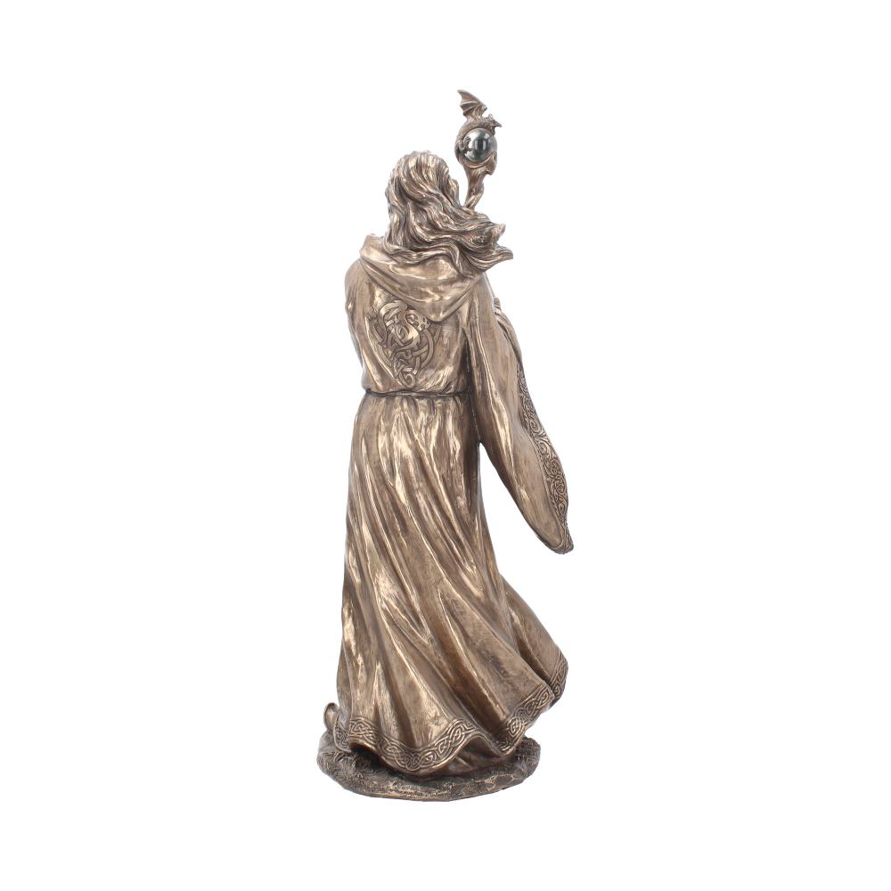 A bronze-colored statue depicts a cloaked figure holding a staff adorned with a globe and bird. The figure stands on a textured base, suggesting motion in an undefined setting.