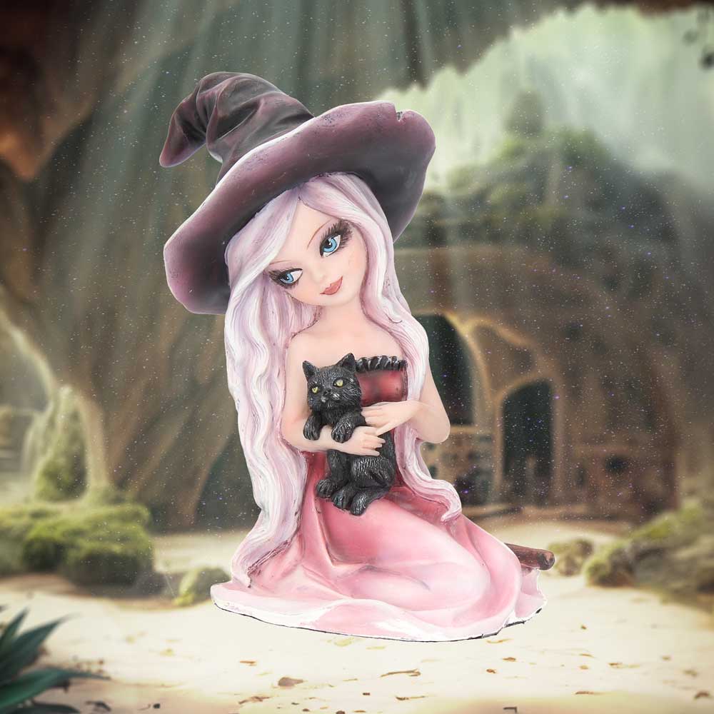 A figurine of a girl with long white hair and a wide-brimmed hat holds a black cat. She is dressed in a pink dress, sitting in a mystical forest setting.