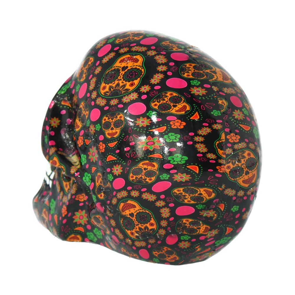 A black skull is adorned with colorful Day of the Dead-style sugar skull patterns, featuring flowers and geometric shapes. It rests against a plain white background.