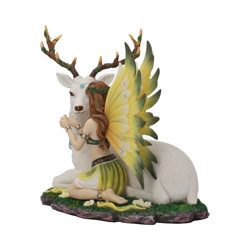 A kneeling fairy with yellow butterfly wings gently touches a white stag's face. They are set on a grassy base decorated with small white flowers.