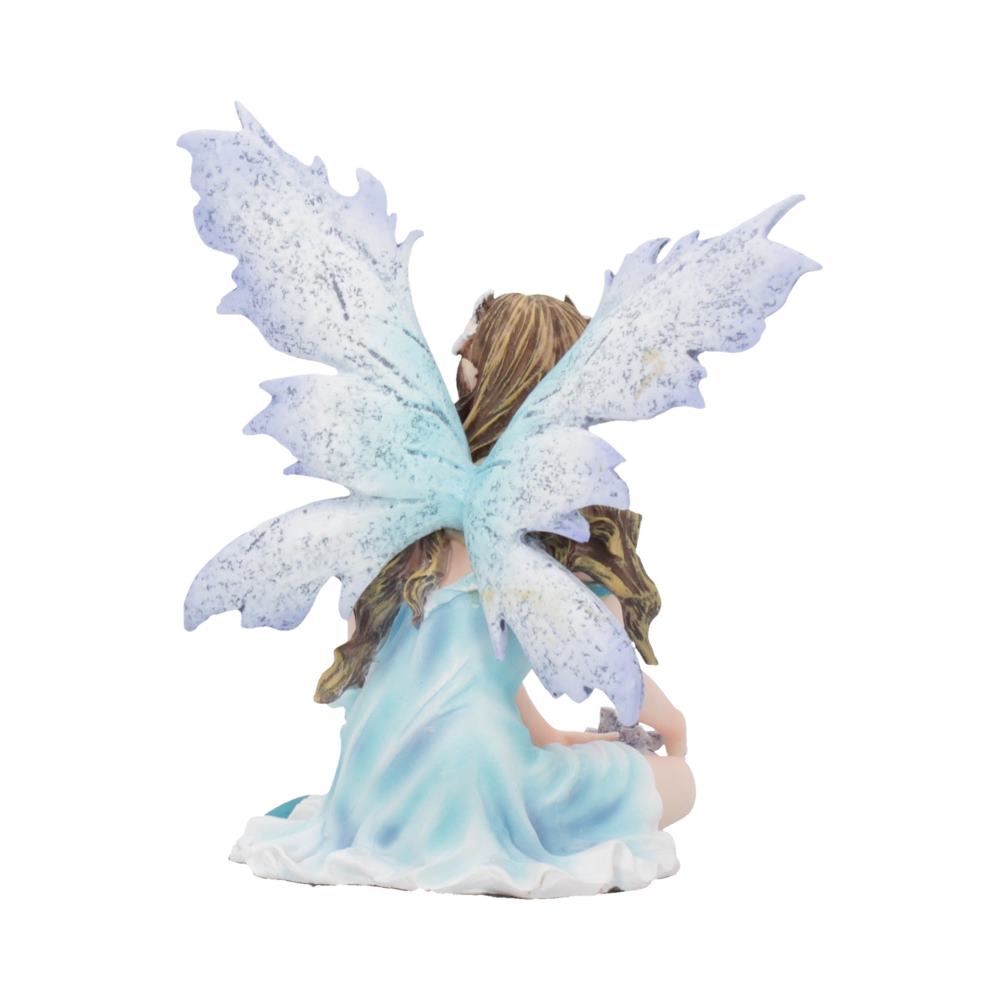 A fairy figurine, seated with translucent azure wings and flowing hair, wears a light blue dress. The pose is calm and serene, set against an isolated white background.