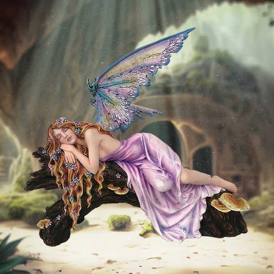 A fairy sleeps serenely on a log covered with mushrooms, nestled in a forest grotto. She has butterfly wings, flowing blonde hair and wears a long, pink gown.