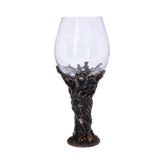 A clear, empty wine glass is held by a sculpted tree trunk. At the base of the tree, small mushrooms add detail, all against a white background.