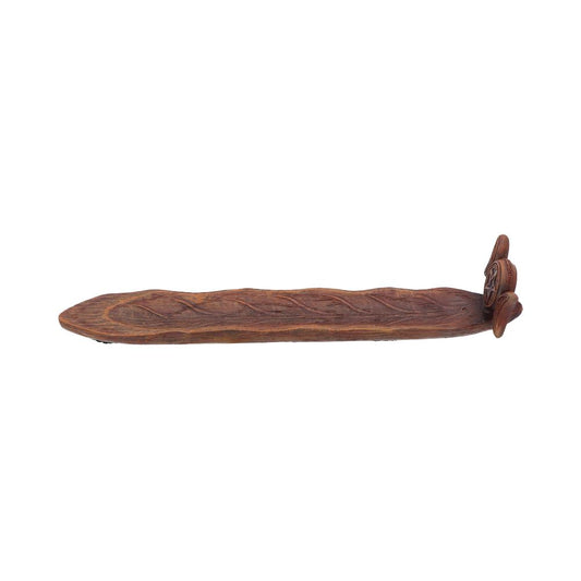 A carved wooden tray rests on a plain white background. The tray is long and narrow with a textured surface and decorative carvings at one end.