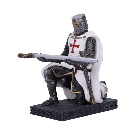 A knight figurine kneels on a patterned base, holding a gray pen-like object horizontally. He wears chainmail and a white cloak with a red cross.