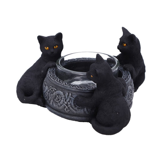 A round candle holder with Celtic knot designs is being guarded by three small black cats with yellow eyes in a white space.