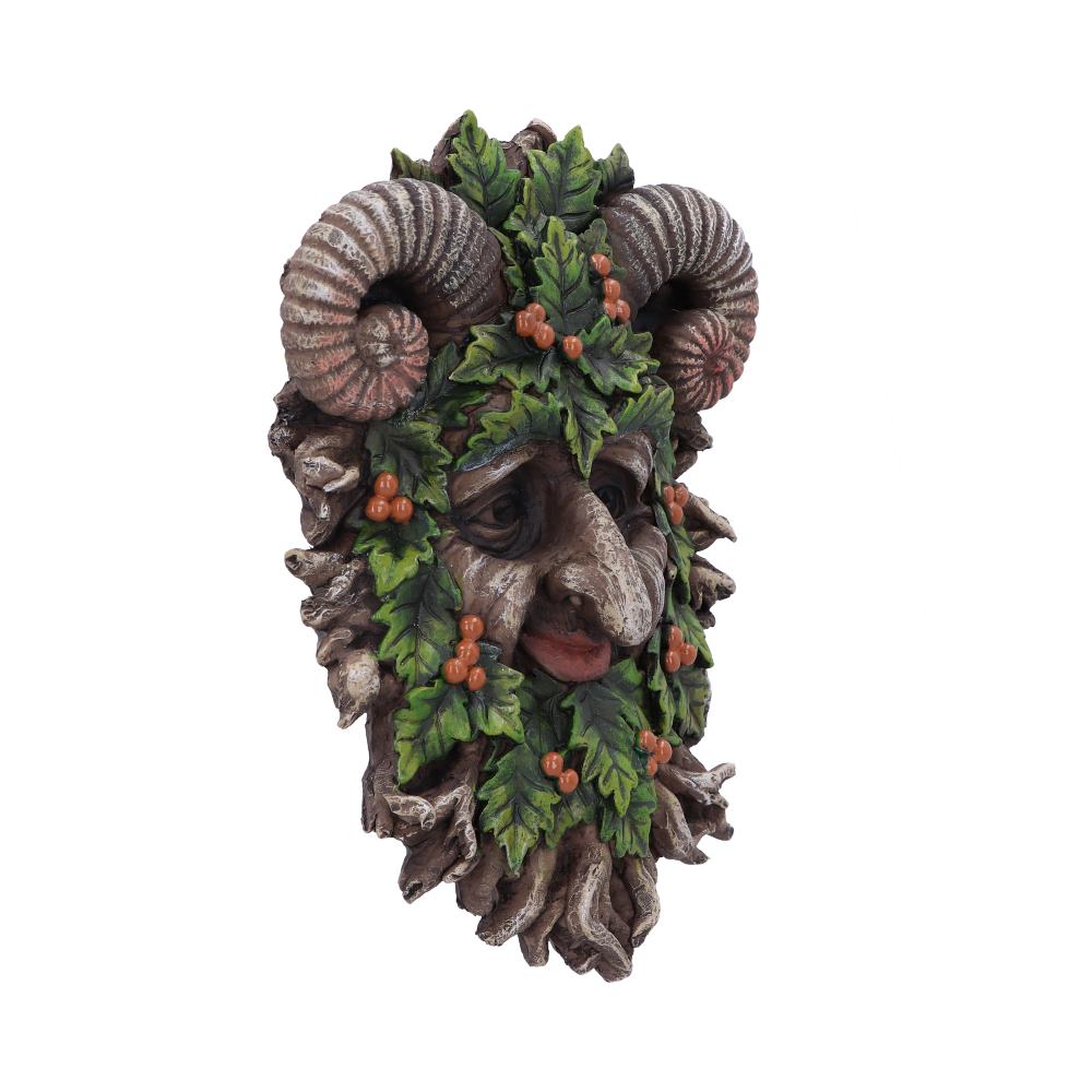 A decorative mask resembles a forest spirit with ram horns, adorned with carved leaves and berries. It rests on a plain, white background.