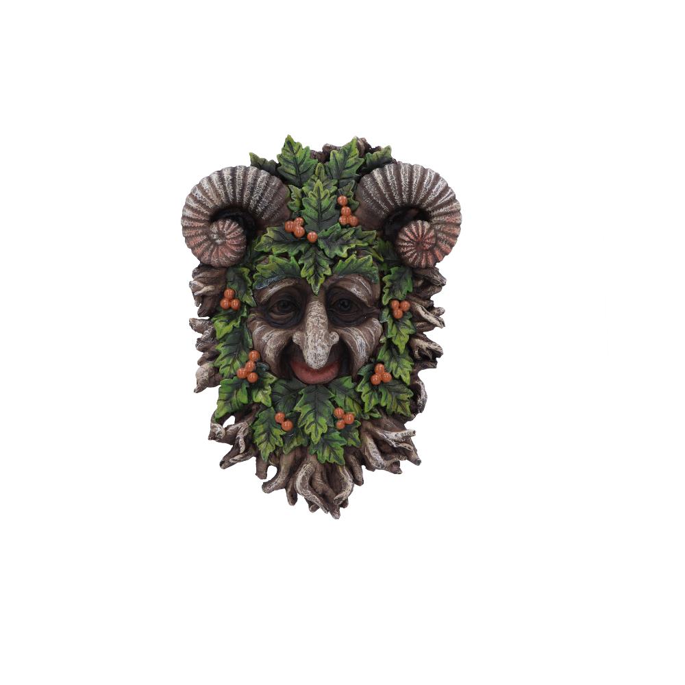 A decorative mask with ram horns and a face surrounded by green leaves and orange berries, smiling mysteriously, set against a plain white background.