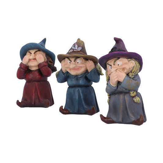 Three witch figurines, posed as "see no evil, hear no evil, speak no evil," wearing colorful hats and robes, stand side by side against a plain background.