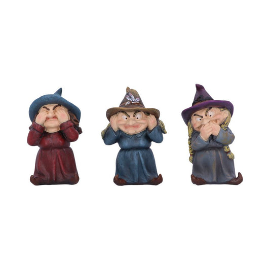Three witch figurines with pointed hats display "see no evil," "hear no evil," and "speak no evil" gestures, set against a plain white background.