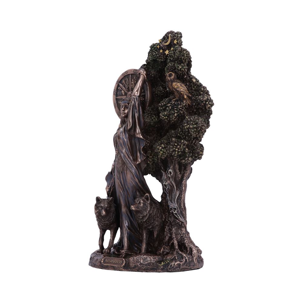 A bronze-colored sculpture depicts a medieval woman with two wolves, standing beside a tree featuring an owl and starry details. The base has the text "ARAWNODD."