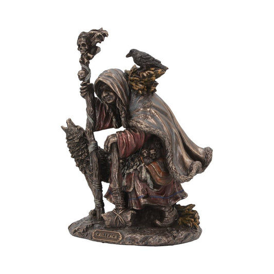 A bronze-colored statue depicts a cloaked figure with a staff topped by a skull, carrying a wolf pelt. A crow perches on their shoulder. Text reads: “CAILLEACH” on the base.