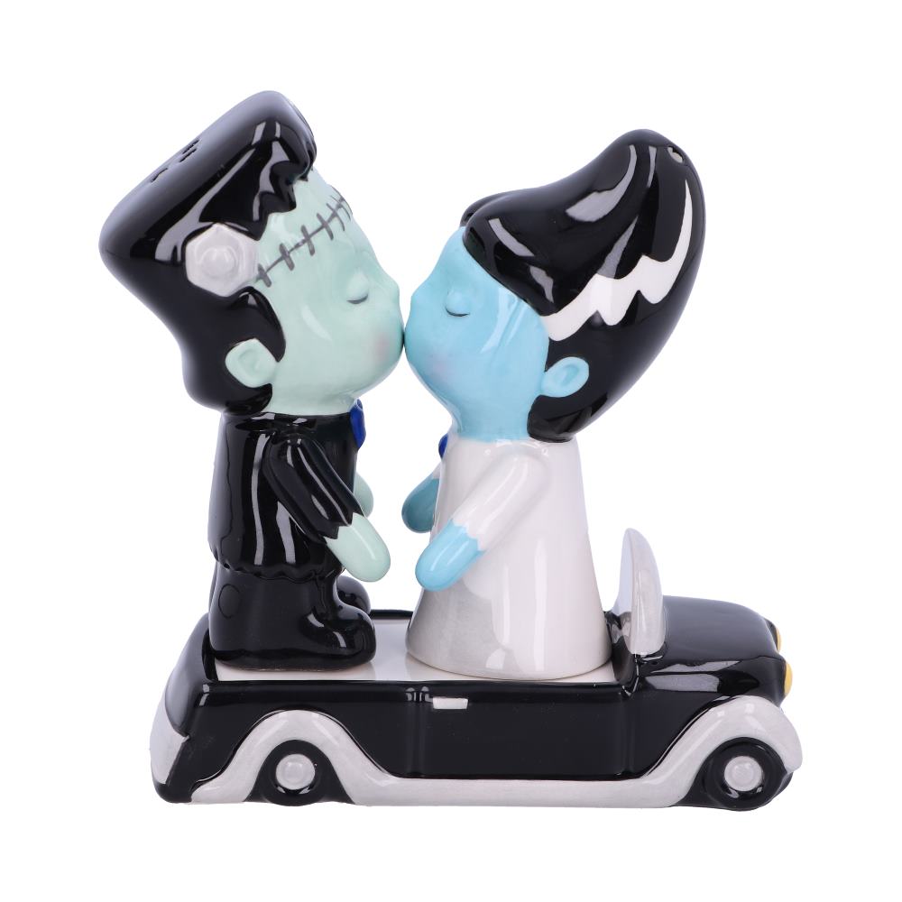 Frankenstein and his bride, ceramic figurines, kiss atop a classic black car.