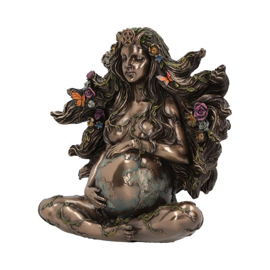 A bronze-like sculpture of a woman sits cross-legged, cradling Earth. Her hair features flowers and butterflies, and a pentagram adorns her head, evoking themes of nature and spirituality.
