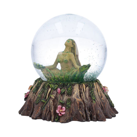 A female figurine sits cross-legged in a glass sphere atop a tree stump base, adorned with flowers and mushrooms. The figurine appears to be made of a material resembling moss or lichen.