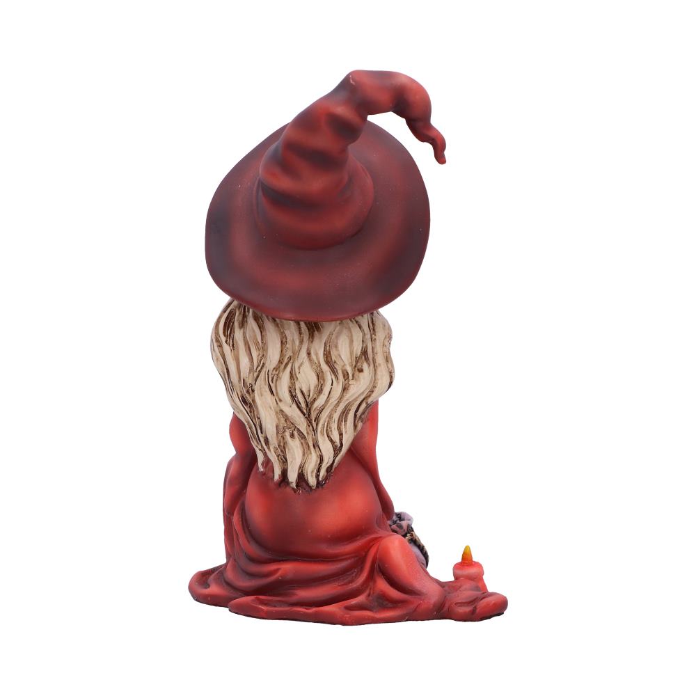 A small, seated gnome figurine with long hair and a red pointy hat sits adjacent to a tiny, lit candle, isolated against a white background.