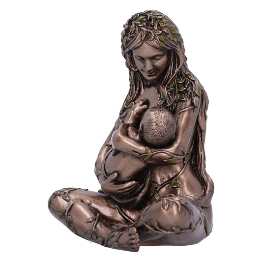 A statue of a mother sits cross-legged, gazing down and cradling a baby in her arms. She and the child are adorned with leaves on a plain white background.