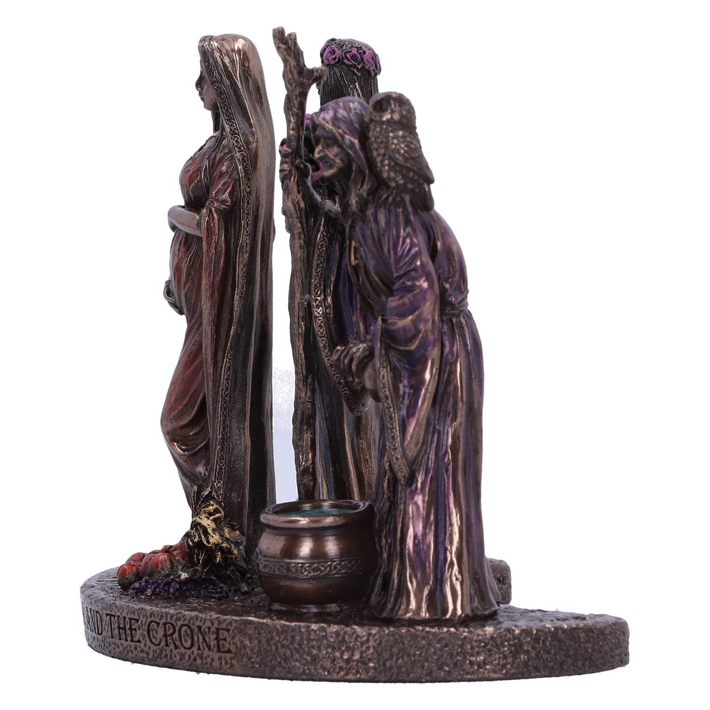 Bronze-toned figures stand in a line, seemingly representing the maiden, the mother, and the crone; all atop a base that is inscribed with the words “AND THE CRONE.”