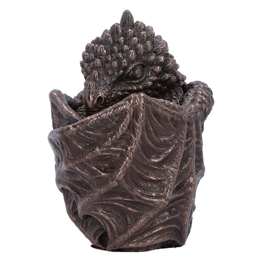 A detailed, bronze-toned dragon sculpture rests inside an intricately designed egg, appearing to emerge. The textured surface mimics scales and waves, evoking a mythical and dynamic presence.
