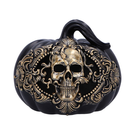 A black pumpkin features an ornate metallic skull design embossed on its surface, set against a plain white background.