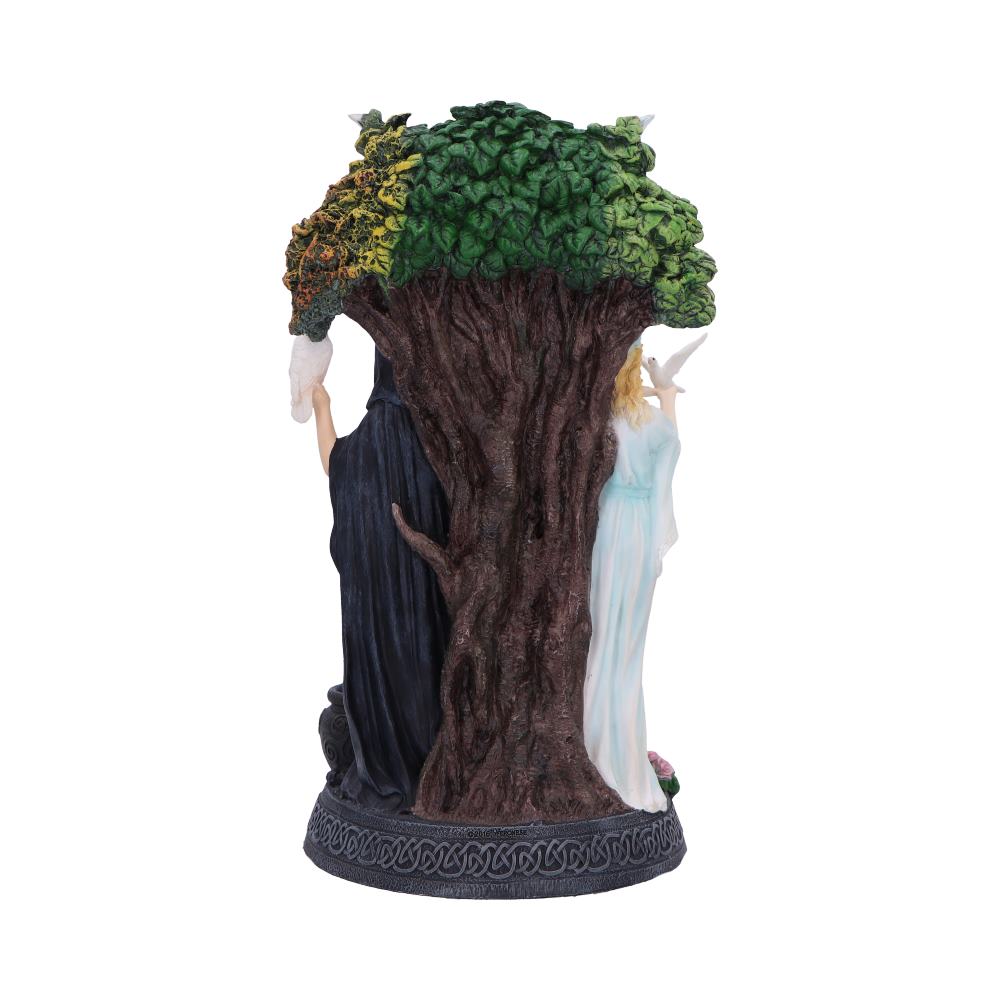 Sculpture presents a tree with two women holding doves, one in a black dress and one in a white dress. The tree has a multi-colored leaf pattern: yellow, orange, and green.