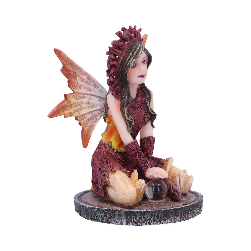 A fairy figurine sits on a circular base, holding a crystal ball. She wears a reddish-brown dress and has large wings. The setting is isolated on a white background.