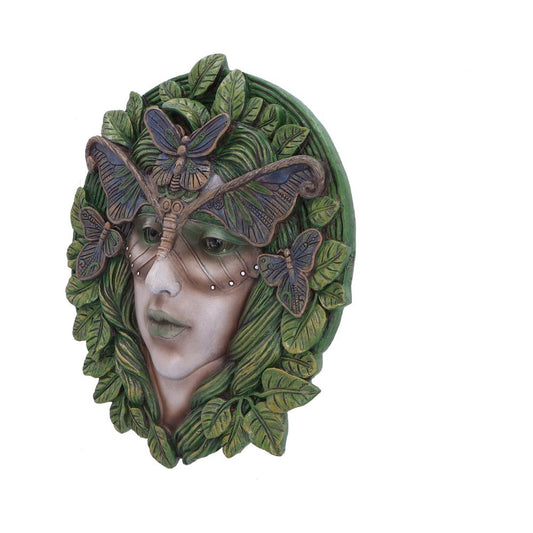 A sculpted face resembling a human is adorned with moths and surrounded by green leaves, creating a nature-inspired mask effect against a plain white background.