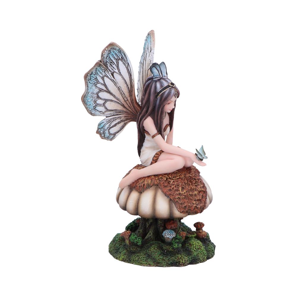A fairy figurine sits atop a mushroom, holding a small bird, surrounded by additional mushrooms and greenery, showcasing a whimsical fantasy setting.
