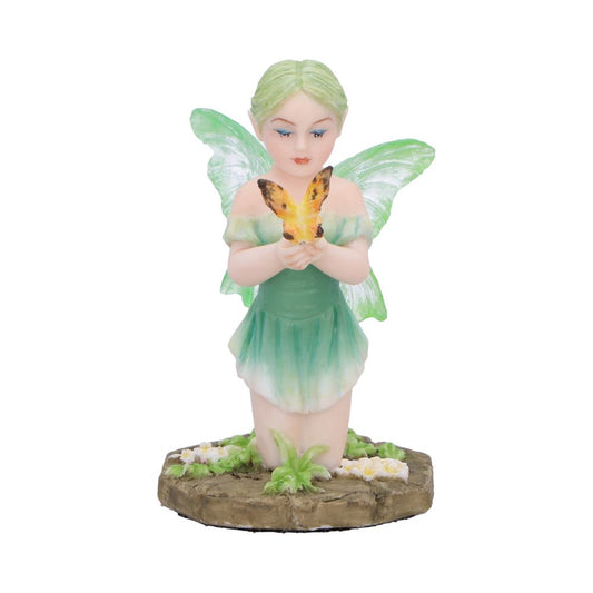 Fairy figurine kneels and gently holds a yellow orange butterfly in both hands while resting on a small flower-strewn stone base against a plain white background.