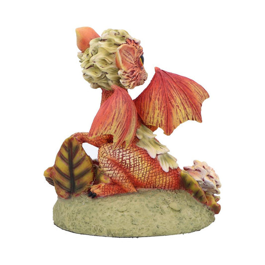 Small sculpted dragon sits on a textured green base, wings partially raised, orange and yellow scales with leaf-like mane, curled tail and decorative leaves against a plain white background.