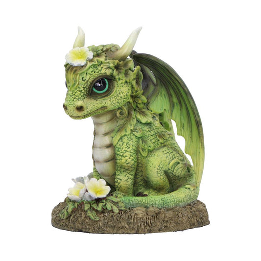 Green dragon figurine sits gazing forward on a textured earth base adorned with white-yellow flowers, folded wing and leaf-like scales, small horns and a large teal eye.