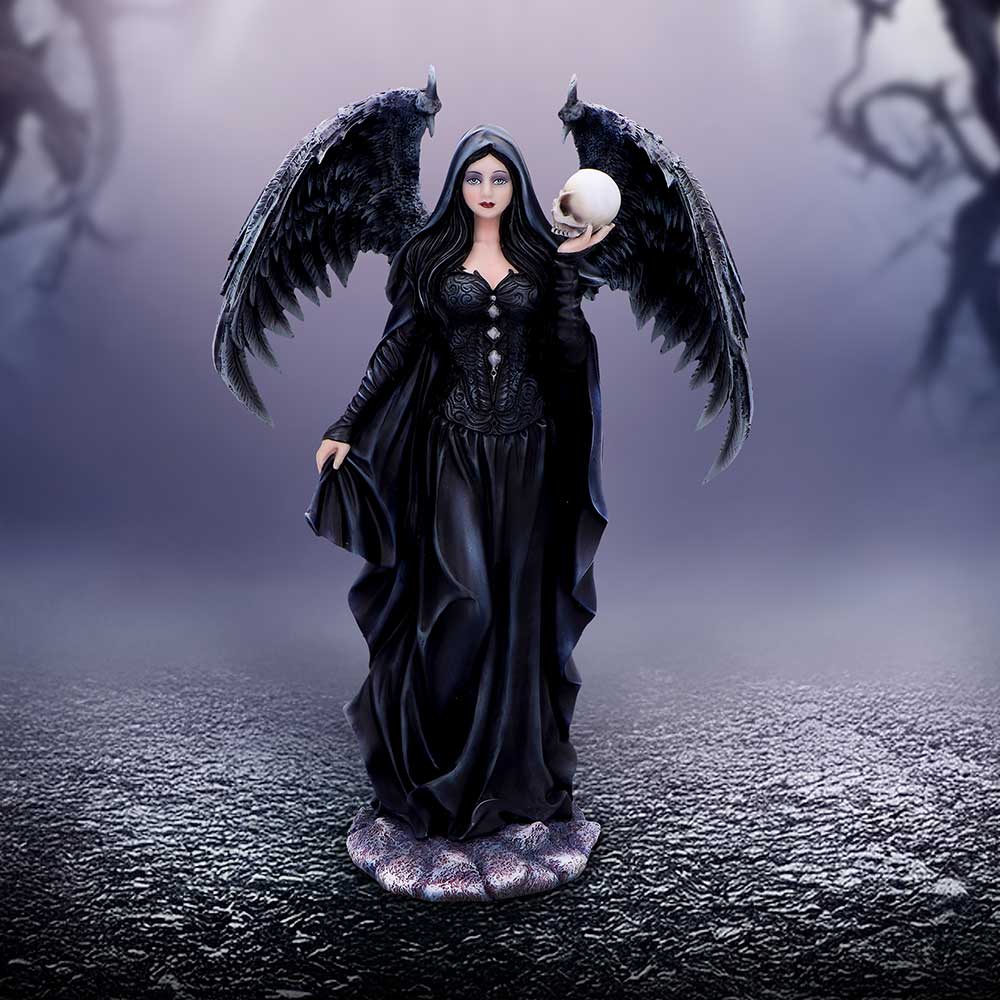 Dark-winged female figure stands in a flowing black gown holding a skull aloft, her hooded face calm against a foggy purple backdrop with cracked ground and shadowy barren tree branches.
